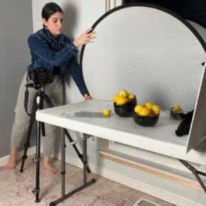 Eva Kashat holding a diffuser to block out harsh light from window during photoshoot